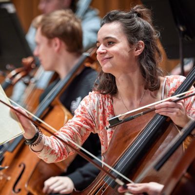 Cellist turning the page of their sheet music in a rehearsal